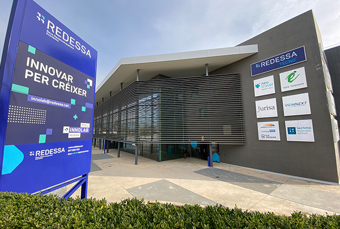Façana principal exterior de l’edifici REDESSA Tecno amb cartells amb els logotips de les empreses intal·lades